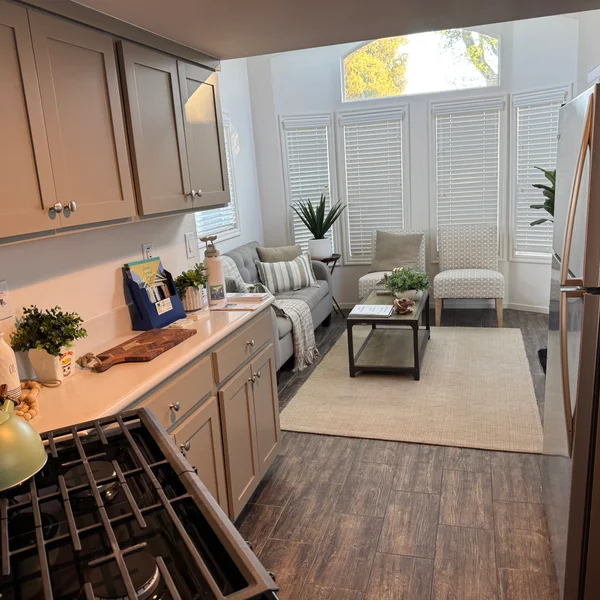 Real estate interior features a gray kitchen and open living area with lots of natural light.