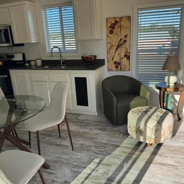 The kitchen area of a manufactured home features white cabinets and an olive green sitting area.