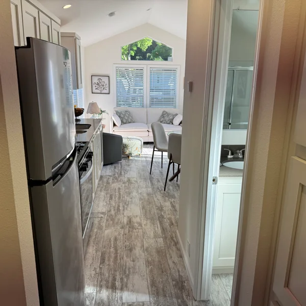 A cozy real estate property featuring a kitchen, living room, and bathroom with neutral tones and light wood flooring.
