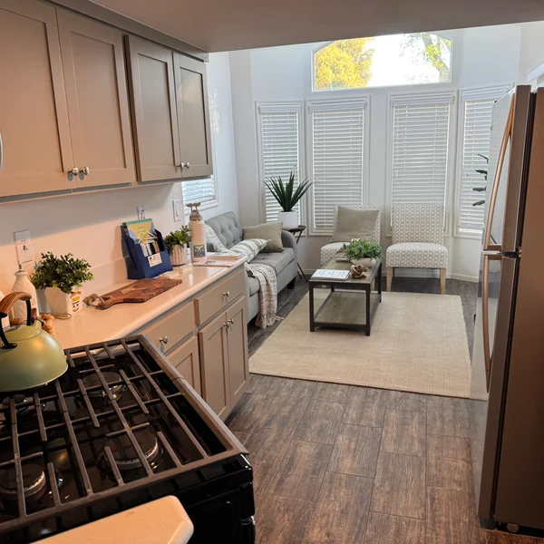 Open floor plan in a real estate property features a kitchen with gray cabinets and living space with large windows.